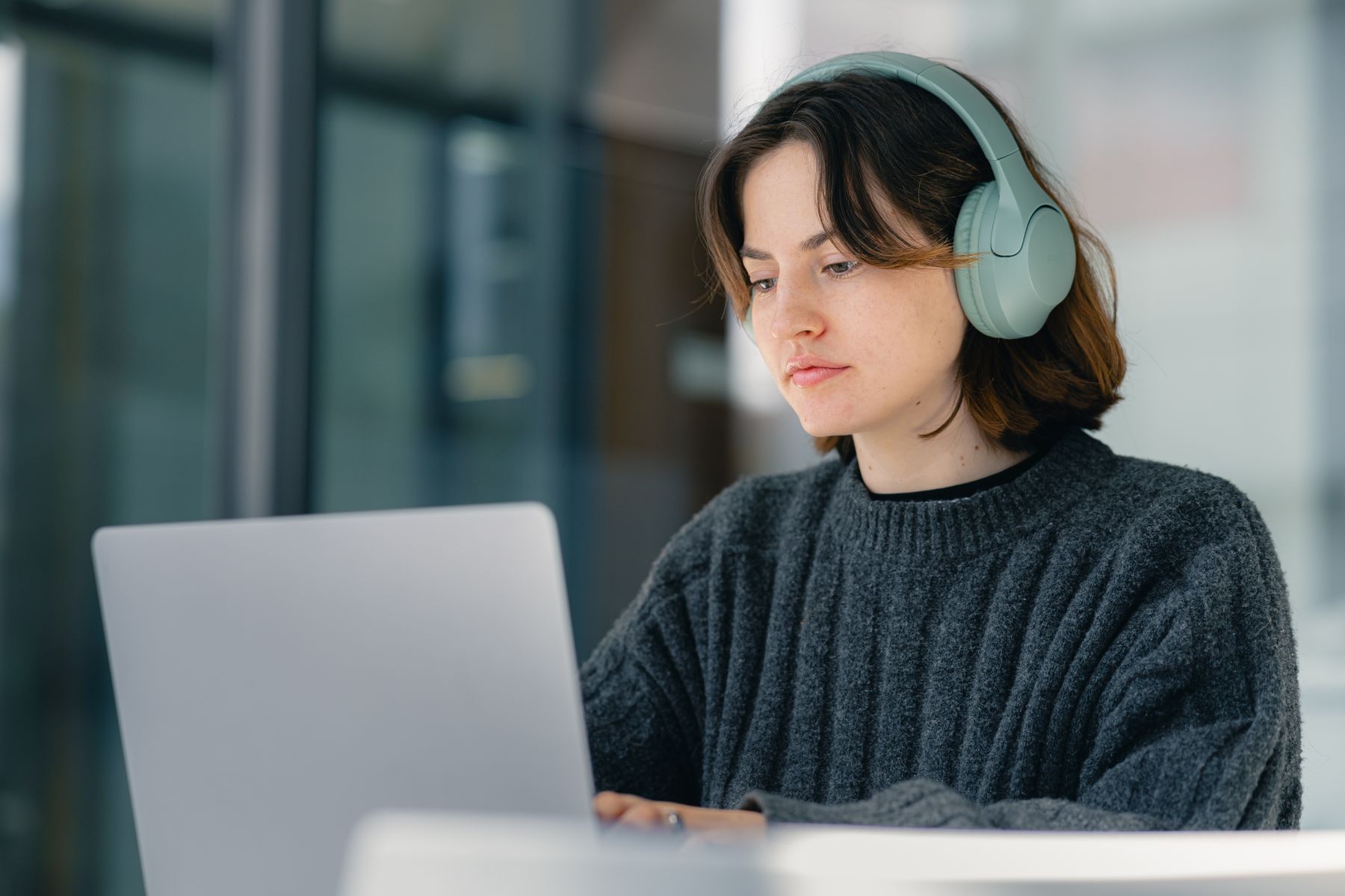 Una mujer estudia con su ordenador portátil y auriculares